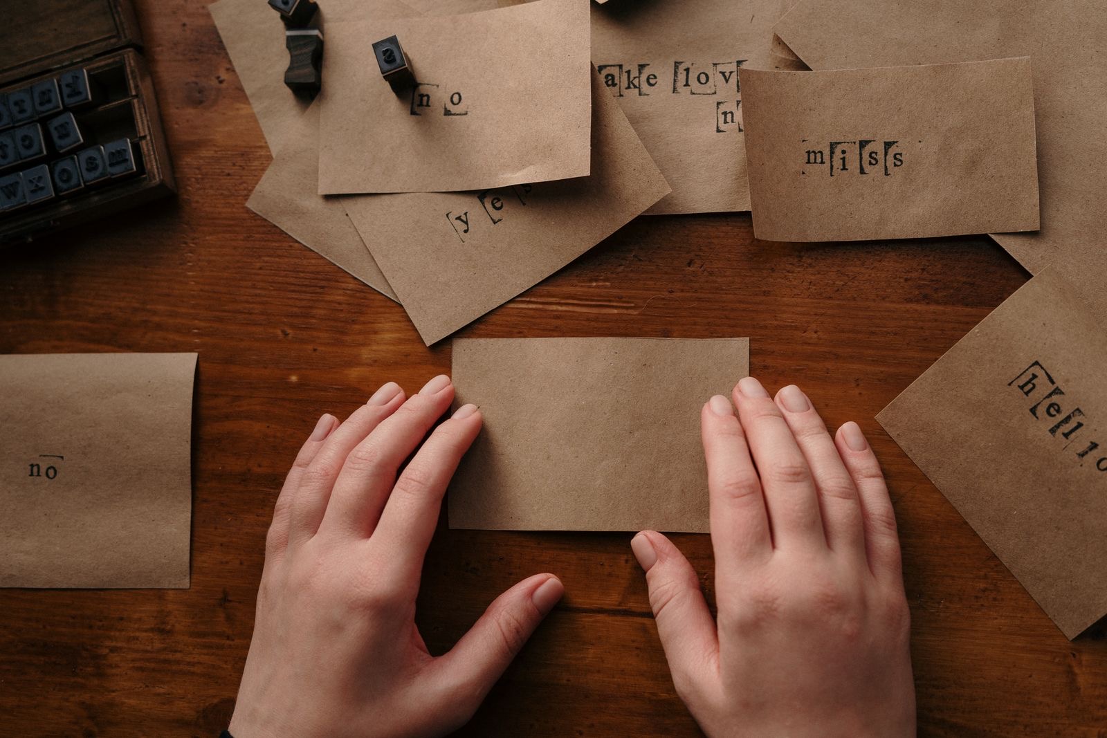 Hands arranging printed certificates and translations on a desk beside a stamp