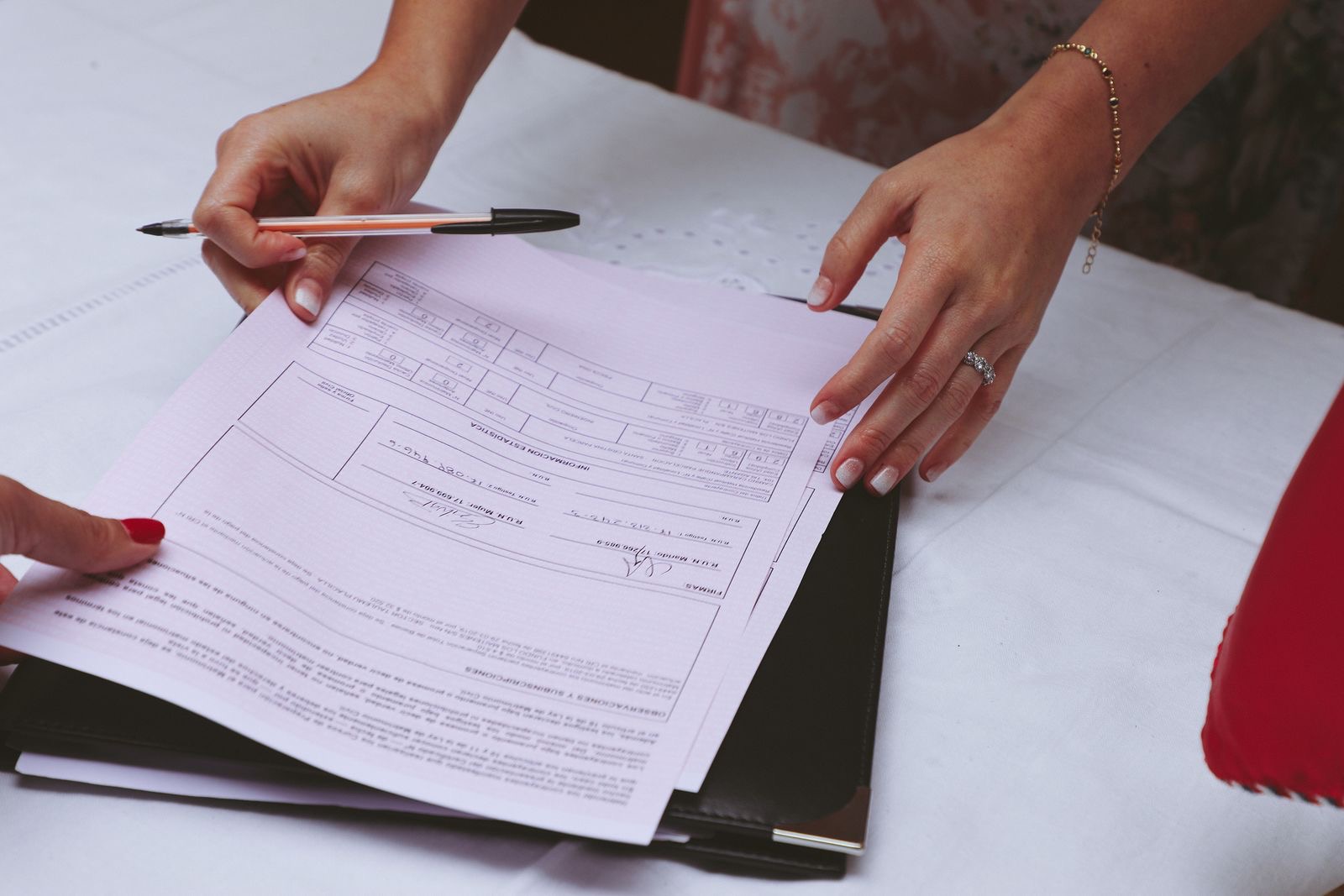 Hands signing papers at a notary's desk