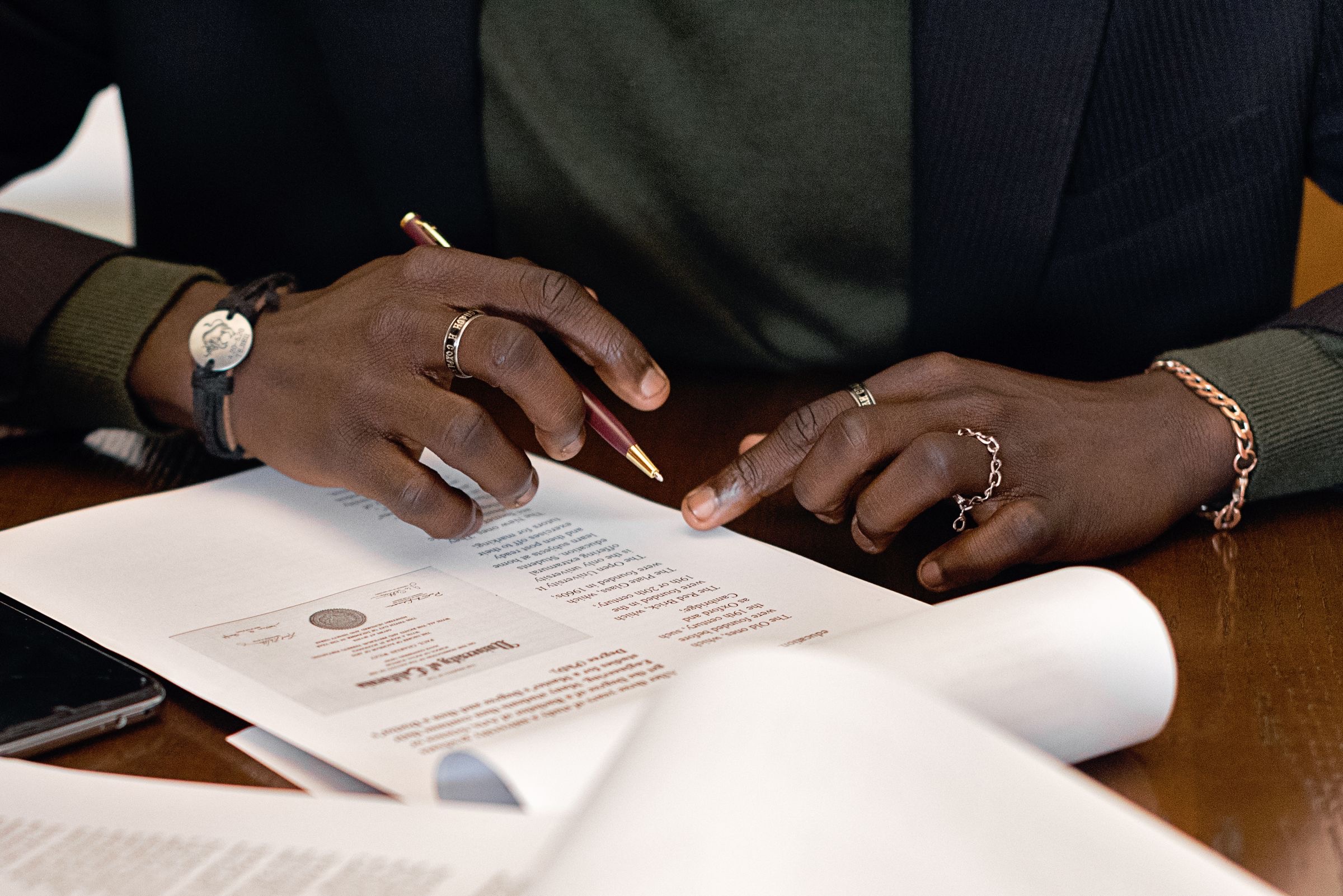 Hands signing a notarial minute on a desk beside a stamp