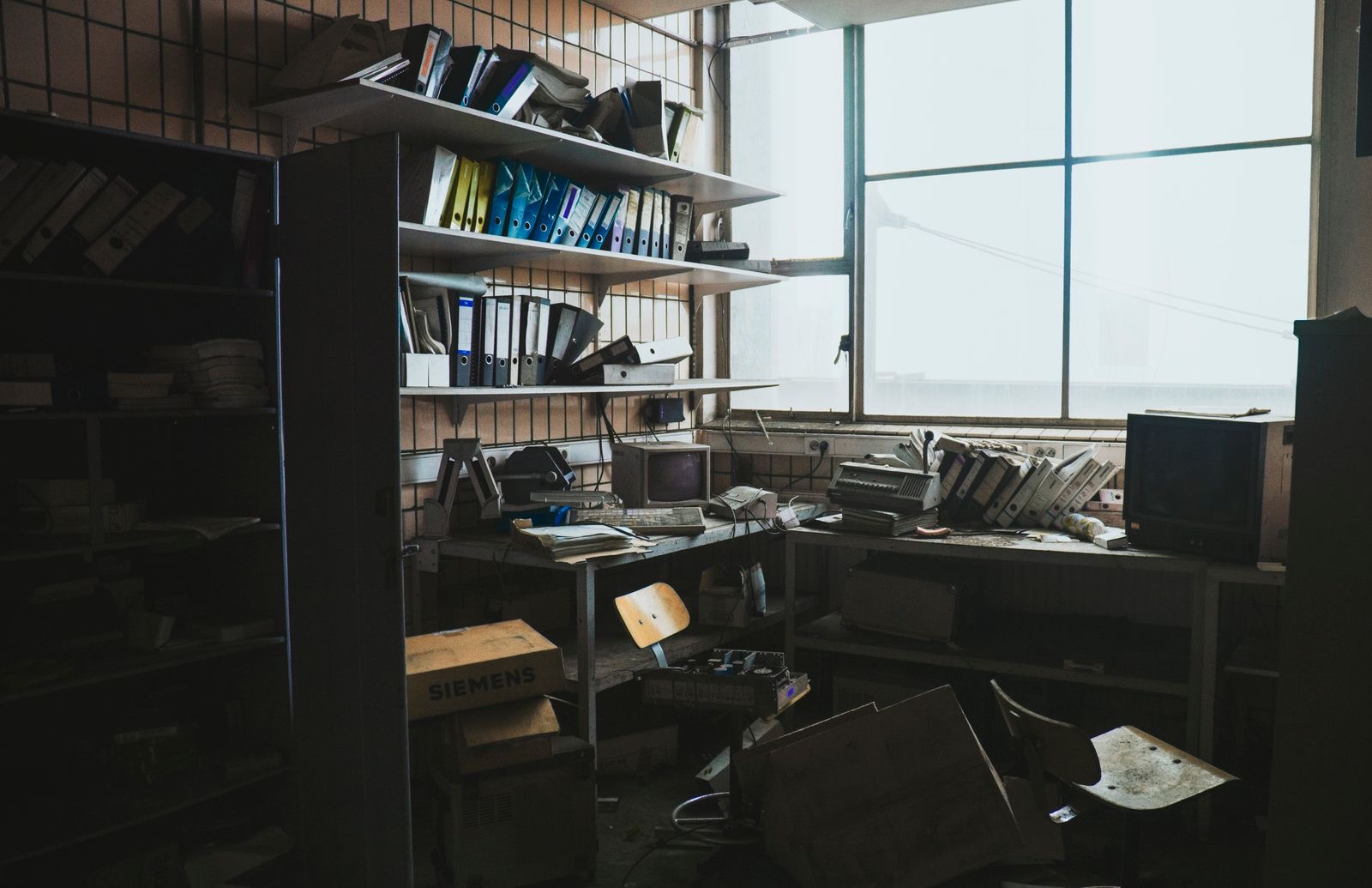 Liquidation file with binders and a laptop on an office desk by a window