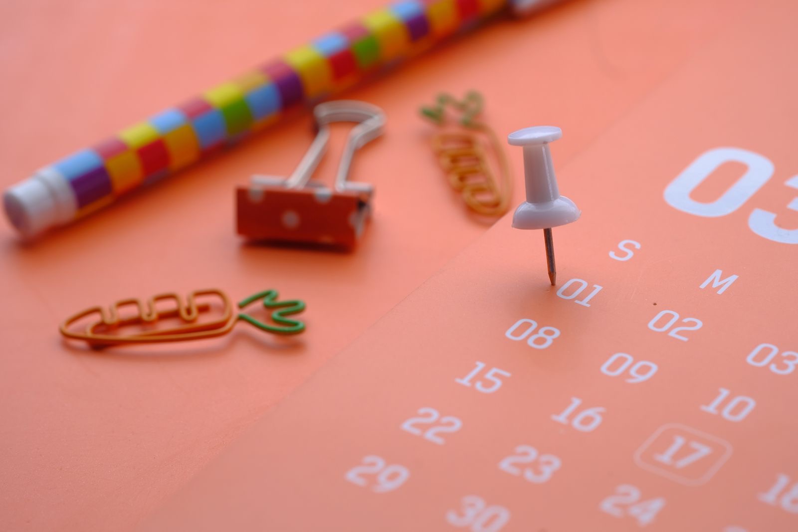 A wall calendar and a pen on a desk