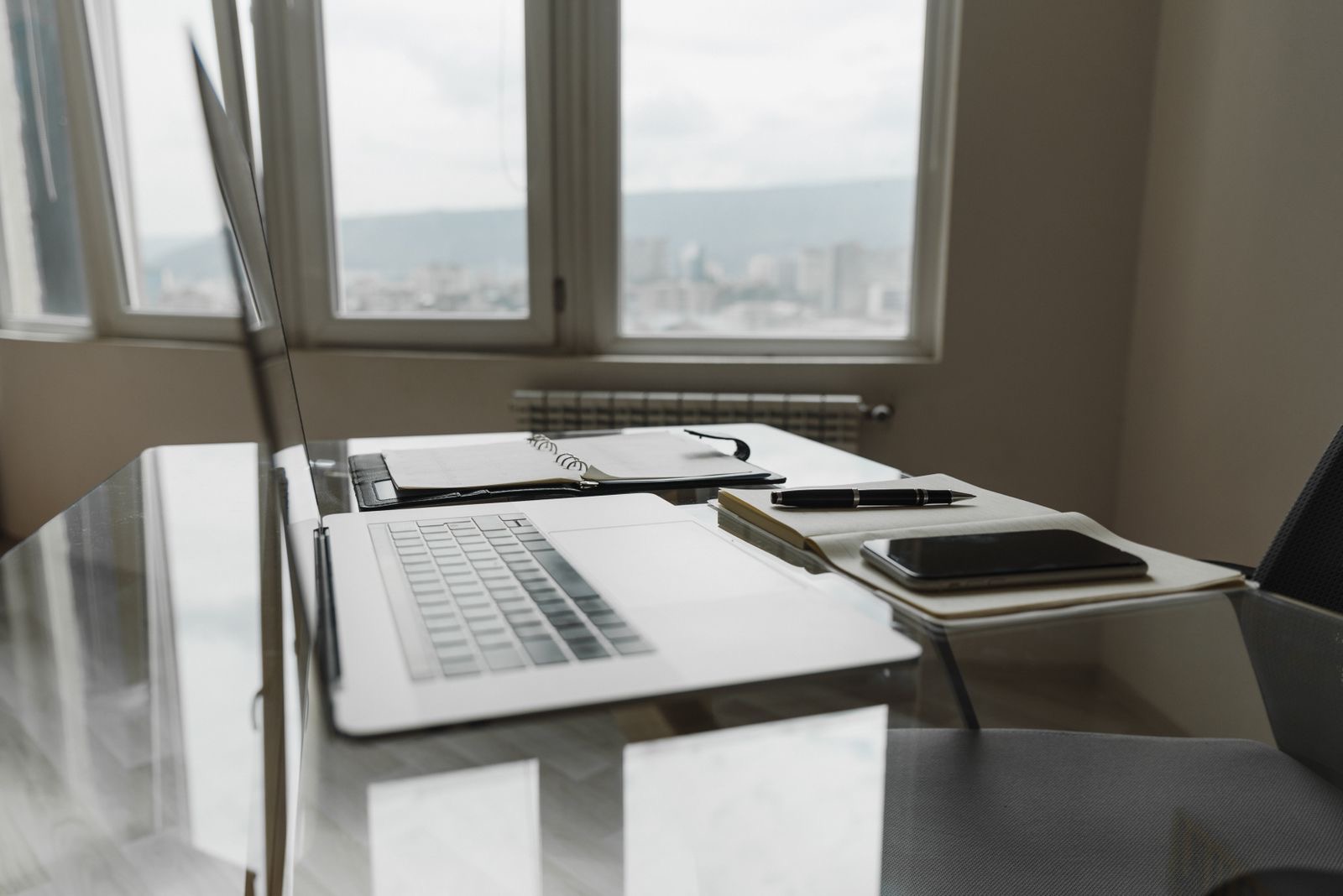 Office desk by a window with document folders and a laptop