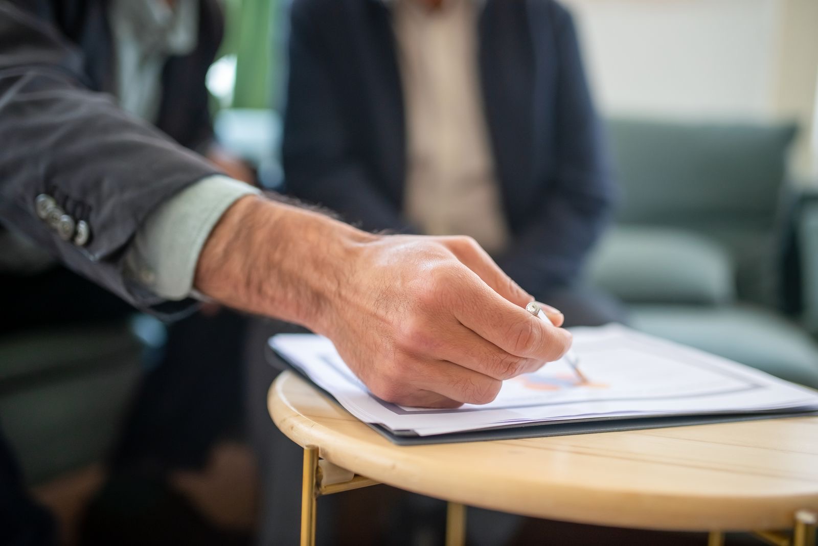 A hand signing a printed form on a desk