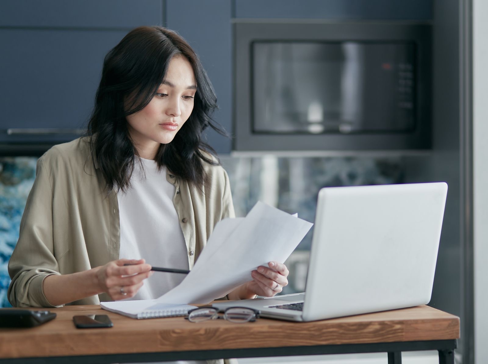 A person reading a company extract at a laptop, the Italian Register on the desk