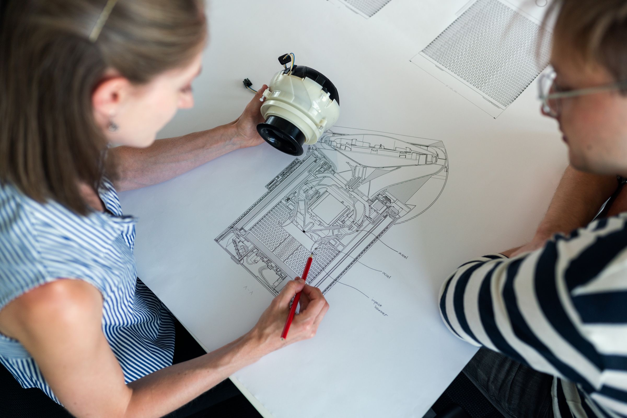 Technical drawing of a mechanical part on a desk beside a pencil and a ruler