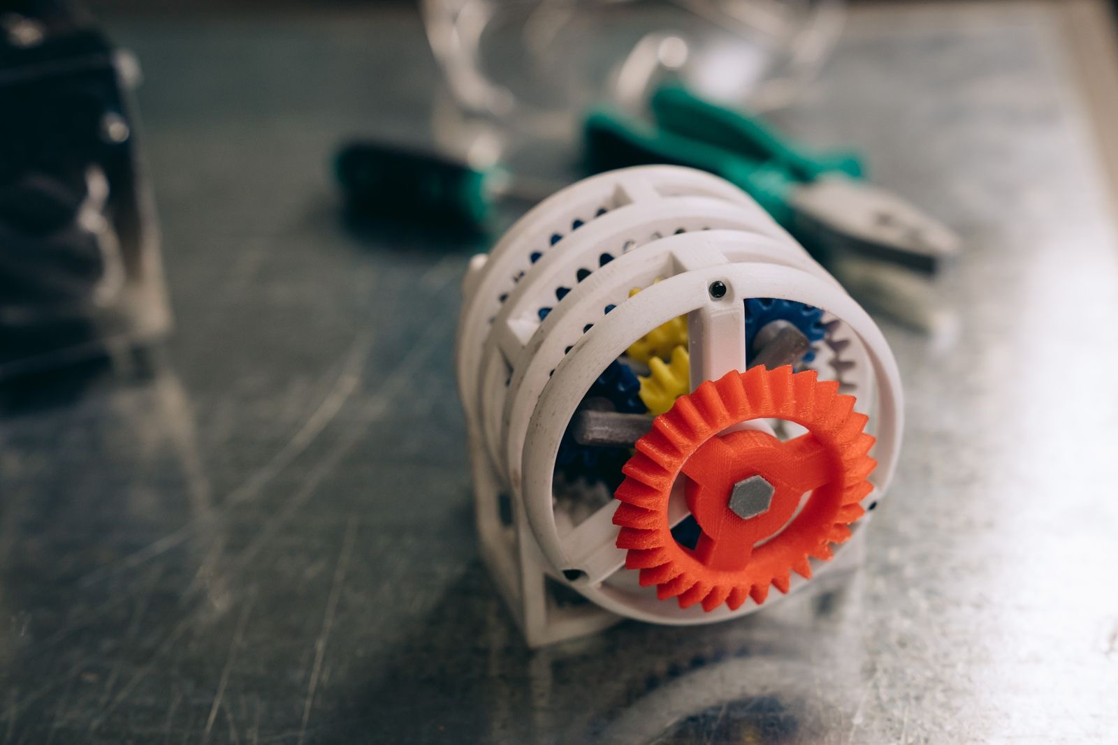 Mechanical prototype on a workbench beside tools and a printed sketch