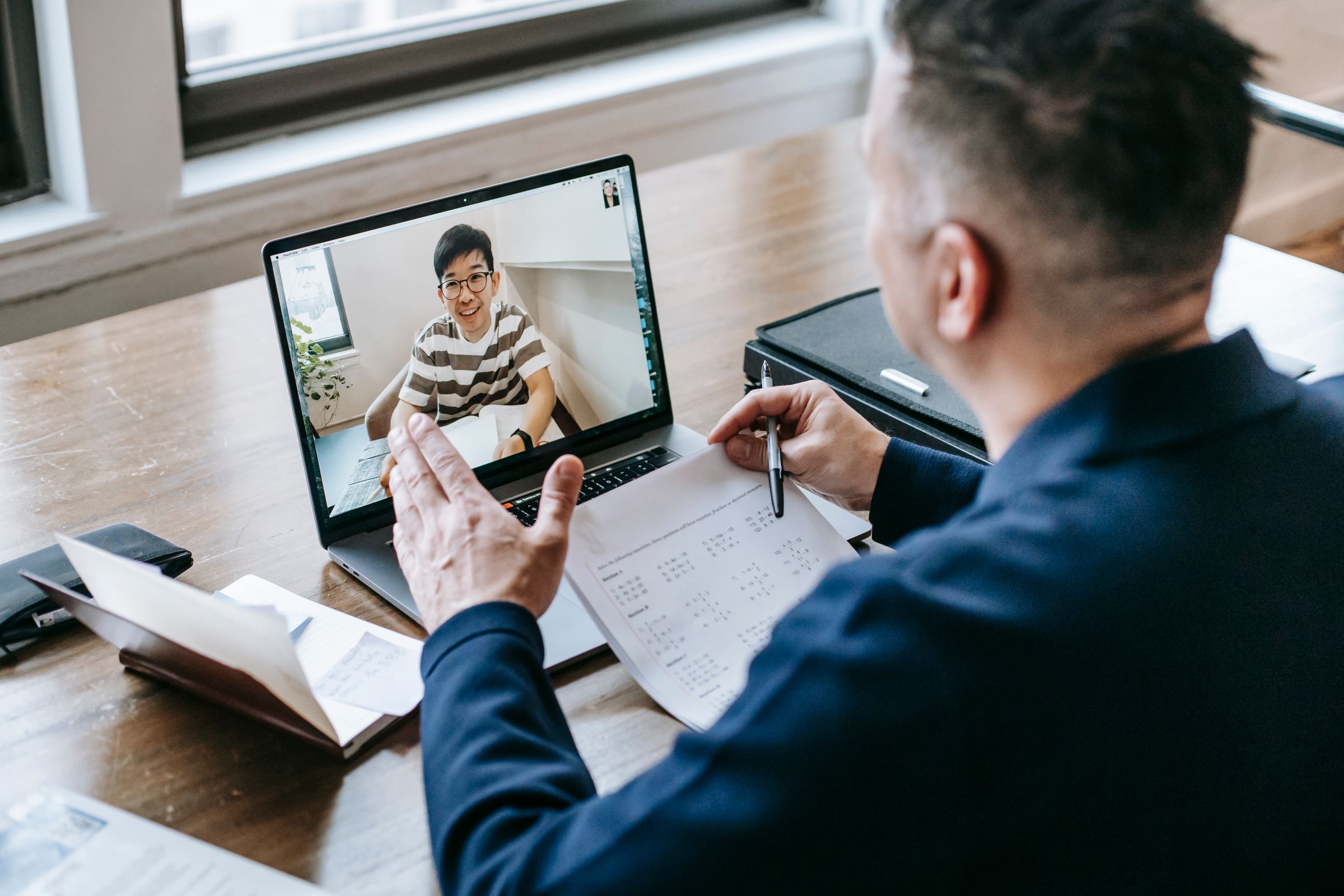A founder on a video call at a laptop, with a calendar and company papers on the desk